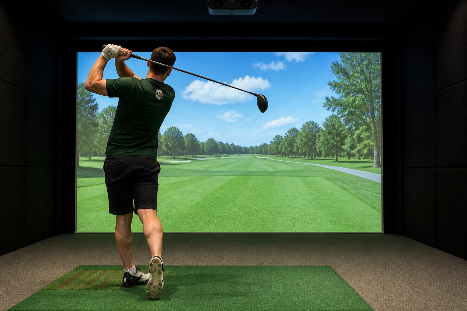 A golfer wearing a Mulligan Bay Golf shirt finishing a drive into an indoor simulator screen